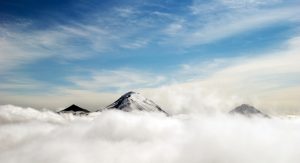 a photo of mountain peaks rising above clouds