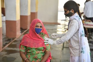 A doctor in India gives an injection to a woman in a sari